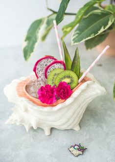 a bowl filled with fruit on top of a table next to a potted plant