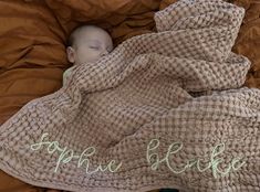 a baby wrapped in a blanket sleeping on top of a brown blanket with the words save the bed written across it