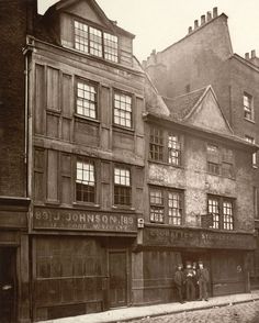 an old black and white photo of two men standing in front of a building on a street corner