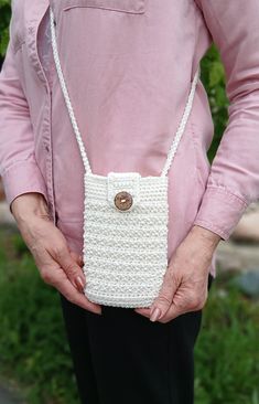 a woman is holding a crocheted purse in her hands and wearing a pink shirt