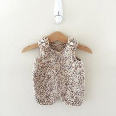 a baby romper hanging on a wooden hanger