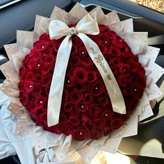 a bouquet of red roses in the shape of a heart with a ribbon on it