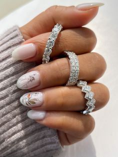 a woman's hand with three different rings on her fingers and one ring in the middle