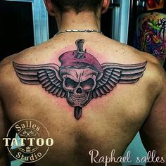 a man's back with a skull and wings tattoo on it