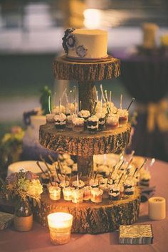 a three tiered cake sitting on top of a table next to cupcakes