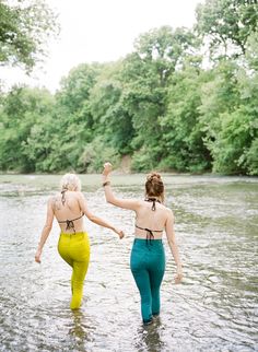 two women walking in the water holding hands