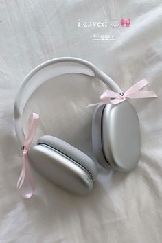 a pair of headphones laying on top of a white sheet with a pink ribbon