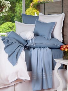 a bed with blue and white comforters in front of a large window that has flowers on it