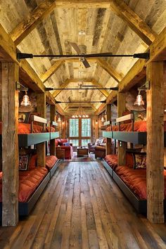 there are many bunk beds in this room with wood flooring and exposed beams on the ceiling