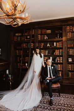 the bride and groom are posing in front of bookshelves