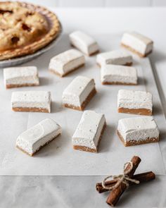 marshmallows and cinnamon sticks are arranged on a baking sheet next to a pie