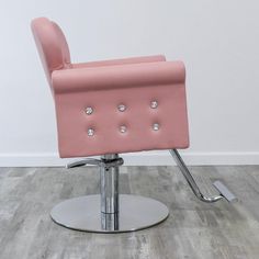 a pink chair with chrome legs and diamond studs on the back is sitting in front of a white wall