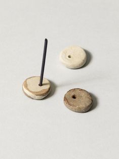 two wooden buttons and a black stick on a white surface