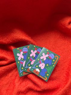 two cards are sitting on top of a red blanket