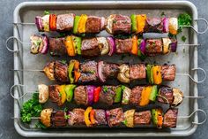 skewered steaks and vegetables are on a tray with garnishes