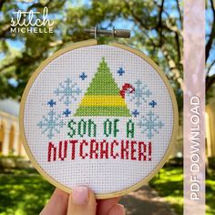 someone is holding up a cross - stitch christmas ornament that says son of a nutcracker