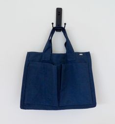 a blue bag hanging from a hook on a white wall with the bottom section open