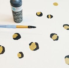 a pen and some paint sitting on top of a white table cloth with black dots