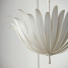 a white chandelier hanging from the ceiling with feathers on it's back