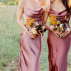 two beautiful women standing next to each other in long dresses with flowers on their heads