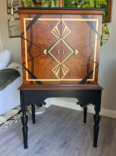 a wooden cabinet sitting on top of a hard wood floor next to a potted plant