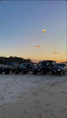 a group of trucks parked on top of a sandy beach