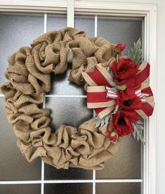 a burlock wreath with red flowers on the front door sill and ribbon