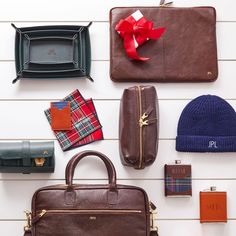 many different types of purses and accessories laid out on a white wall with red ribbon