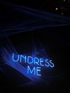 a neon sign that says underest me in blue light on a dark background with the word underneath it