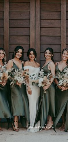 a group of women standing next to each other wearing dresses and holding bouquets in their hands