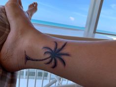 a person's foot with a palm tree tattoo on the left side of their leg