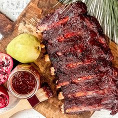 a large piece of meat sitting on top of a cutting board next to some fruit