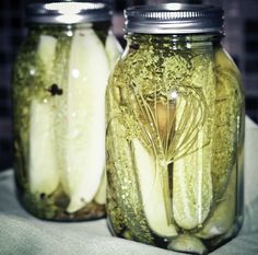 two jars filled with pickles sitting on top of a table