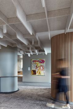 a blurry photo of a person walking in an office building with large circular wooden columns