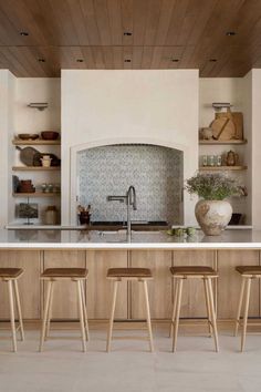 a kitchen with wooden shelves and stools in front of the counter top, along with an oven