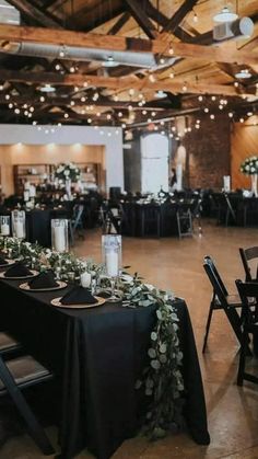 the tables are set up with black linens and greenery for an elegant reception