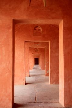 an empty hallway with orange walls and arches