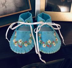 a pair of blue baby shoes sitting on top of a table next to a framed photo