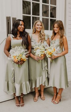 three bridesmaids standing in front of a white door and holding their bouquets