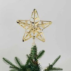 a gold star ornament on top of a green christmas tree with pine needles