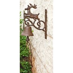 a metal bell mounted to the side of a building with a deer head on it