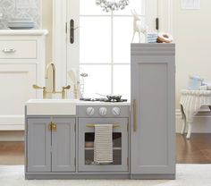 a kitchen with an oven, sink and cabinets next to a window in the room