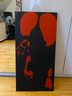 a black and red painting with two balloons on it's face in front of a white wall