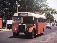 an old red and white bus is driving down the street in front of some cars