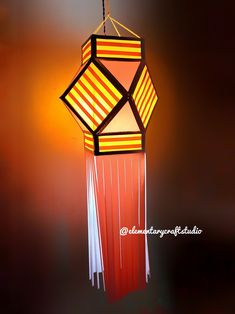 a red and yellow lamp hanging from a ceiling in a room with dark lighting behind it