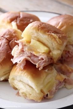 ham and cheese sliders stacked on top of each other on a white plate with a wooden table in the background