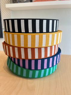 four different colors of ribbon sitting on top of a wooden table in front of a shelf