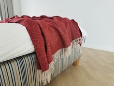 a bed with a red blanket on top of it next to a wooden foot board