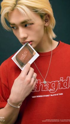 a young man with blonde hair holding up a card