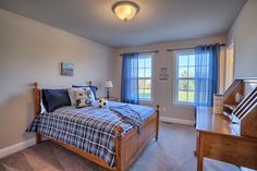 a bedroom with a large bed and two windows